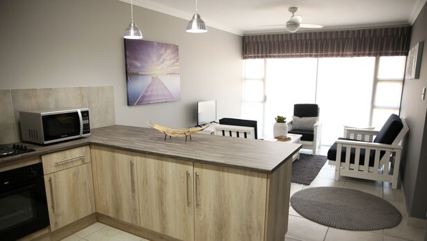 A modern kitchen with a wooden island, a microwave, and a dining area with a chair and table.