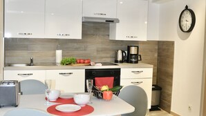 Une cuisine moderne avec des meubles blancs, un plafond en bois et un coin repas comprenant une table et des chaises.
