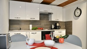 Une cuisine moderne avec des meubles blancs, une horloge au mur et une table à manger dressée avec des assiettes et des verres.