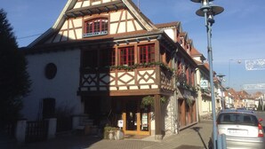 Un bâtiment traditionnel à colombages, doté d’une entrée imposante, d’un panneau de signalisation indiquant la présence d’un parking et d’un lampadaire.
