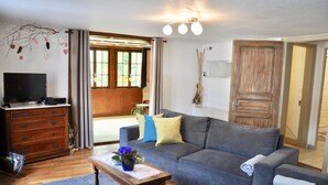 Un salon comprenant un canapé, une table basse, un téléviseur et un meuble en bois.