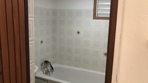 Een badkamer met een bad, toilet en douche.