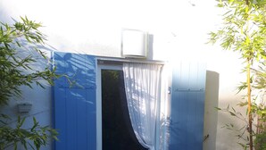 Una puerta azul con una cortina blanca, una ventana pequeña y una rejilla encima.