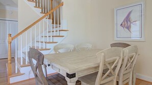 Ein Essbereich mit Holztisch und -stühlen, eine Treppe mit hölzernen Geländern und ein gerahmtes Bild mit Fischmotiven an der Wand.