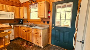 A wooden cabin-style kitchen with a microwave, sink, and wooden cabinets. - Deer Country Vacation Cabins #4 - Long Range View, Dogs Friendly (Waynesville)