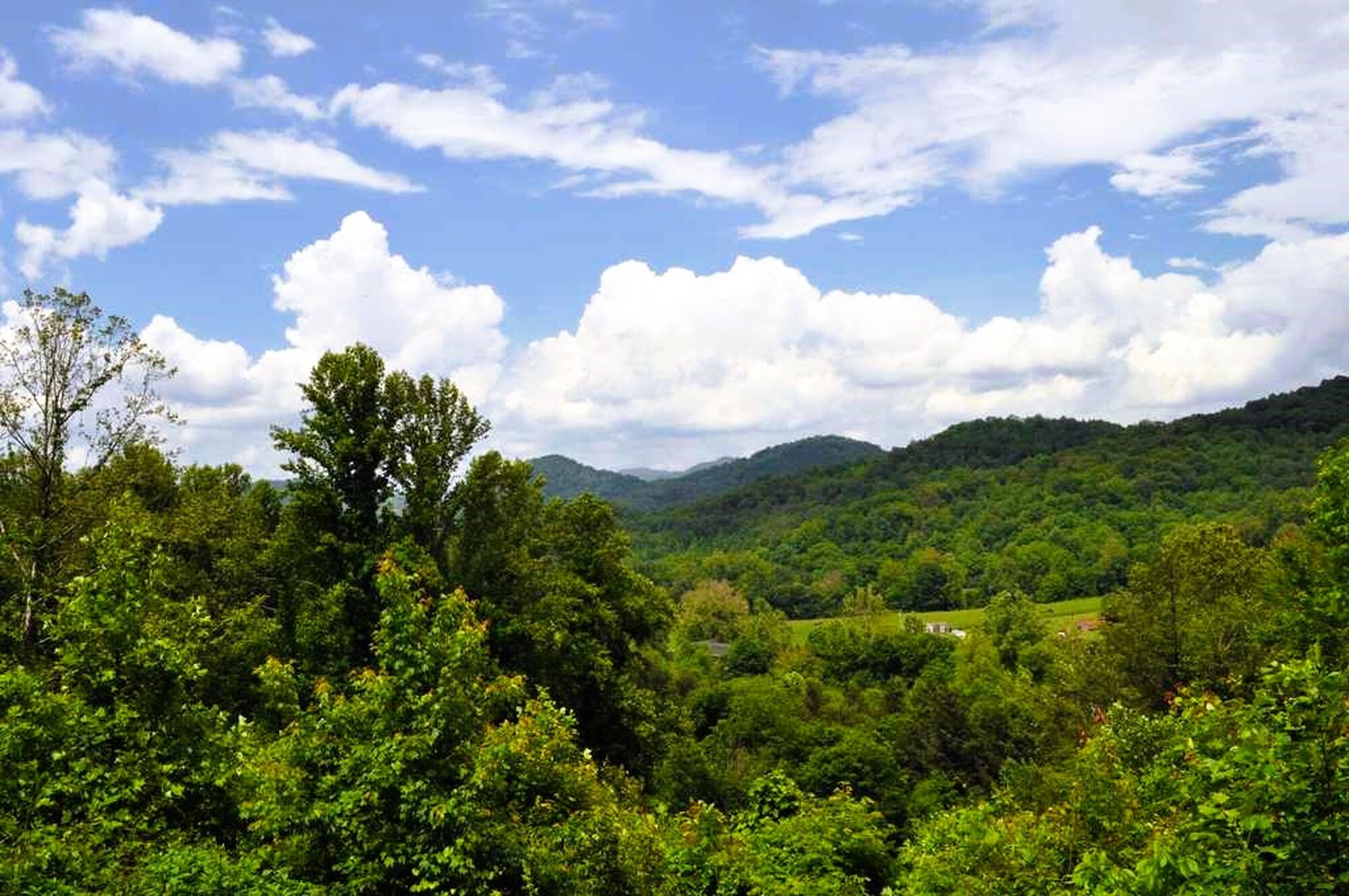 A lush green landscape with a clear sky and scattered clouds.