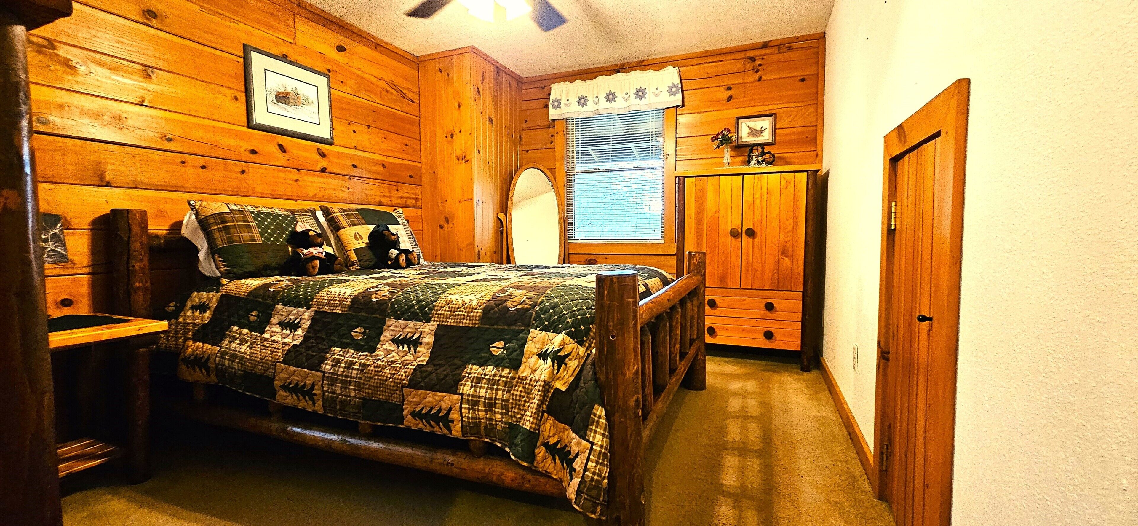 A bedroom with a wooden bed, a dresser, and a window with blinds.