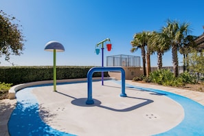 A playground with a blue and white surface, a green and purple play structure, and palm trees in the background. - Oceanfront - Awesome View -  Great Location! Sleeps 8 King, two queens, sofa bed (Orange Beach)