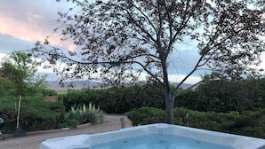 A hot tub in a garden with a tree and a view of the mountains. - Large, Private & Charming retreat is ultimate upscale stay near Cody, Y.S. Park (Ralston)