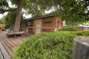 A wooden cabin with a deck, surrounded by dense greenery. - Large, Private & Charming retreat is ultimate upscale stay near Cody, Y.S. Park (Ralston)