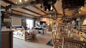 A rustic cabin interior with wooden furniture, a large dining table, and a television. - Large, Private & Charming retreat is ultimate upscale stay near Cody, Y.S. Park (Ralston)