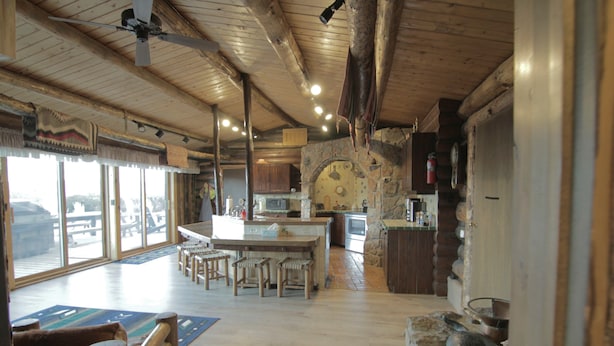 A spacious kitchen with a large island, wooden bar stools, and a stone accent wall. - Large, Private & Charming retreat is ultimate upscale stay near Cody, Y.S. Park (Ralston)
