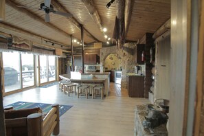 Une cuisine spacieuse dotée d’un grand îlot central, de tabourets de bar en bois et d’un mur d’accent en pierre.