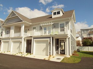 A two-story residential house with a front porch, a garage, and a balcony. - Beautiful Rehoboth Beach Townhouse w/ Pool Sleeps 8 (Rehoboth Beach)