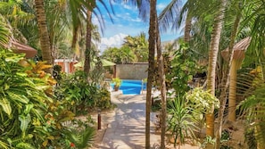 Una piscina rodeada de exuberante vegetación tropical y un cielo azul cristalino.