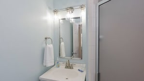 Un bany amb un lavabo blanc, un mirall i una barra de tovalloles.