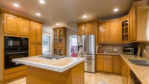 A kitchen with wooden cabinets, a stainless steel refrigerator, a microwave, and a stove.