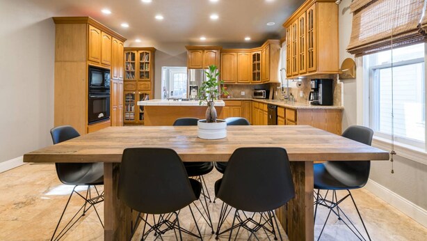 A kitchen with wooden cabinets, a central island, and a dining table with chairs.