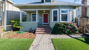 A single-story house with a red front door, a covered porch, and a brick pathway leading to the entrance.