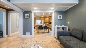 A modern living room with a sofa, a coffee table, and a dining area with chairs and a table.