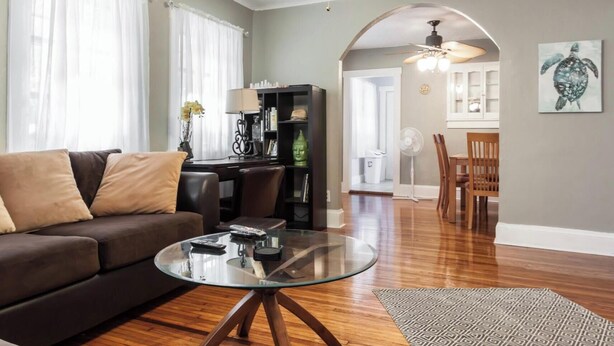 Una sala de estar con un sofá, una mesa de centro y una estantería. Cuenta con una zona de comedor con sillas y una mesa.