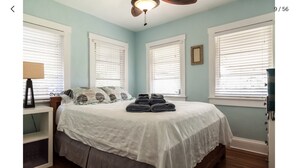 Un dormitorio con cama, una mesita de noche con lámpara y una ventana con persianas.