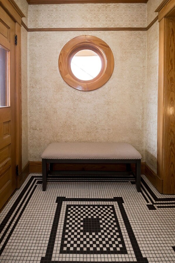A room with a wooden bench, a patterned floor, and a circular window. - B.H. McCarty House, a spacious Local Historic Landmark in Old Town Fort Collins (Fort Collins)