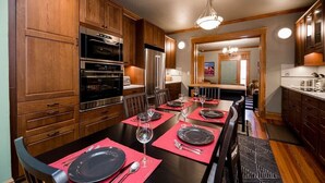 Un coin repas avec des meubles de rangement en bois, une grande table à manger dressée pour six personnes et une cuisine en arrière-plan.