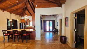 A spacious kitchen with wooden beams, a dining area with chairs, and a large island. - Beautiful Tropical Island Villa for big families and groups (Frederiksted)