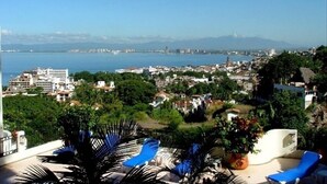 Un paisaje urbano costero con vista al mar y montañas a lo lejos.
