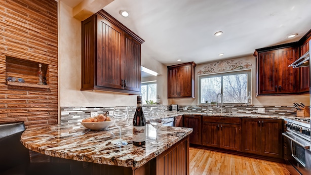 A kitchen with a granite countertop, wooden cabinets, and a large window. - 3 Bedrooms - Gourmet Kitchen - Open Floorplan - Near Red Rocks & Near Downtown (Lakewood)