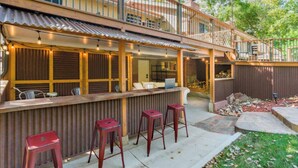 A covered outdoor bar area with a wooden counter, red bar stools, and string lights. - 3 Bedrooms - Gourmet Kitchen - Open Floorplan - Near Red Rocks & Near Downtown (Lakewood)