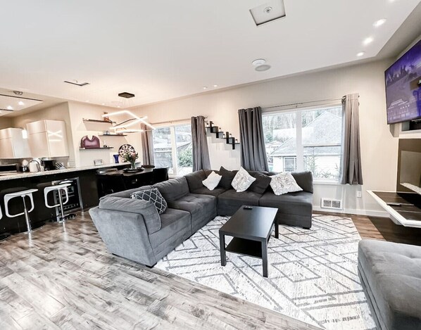A modern living room with a grey sectional sofa, a black coffee table, and a patterned rug.
