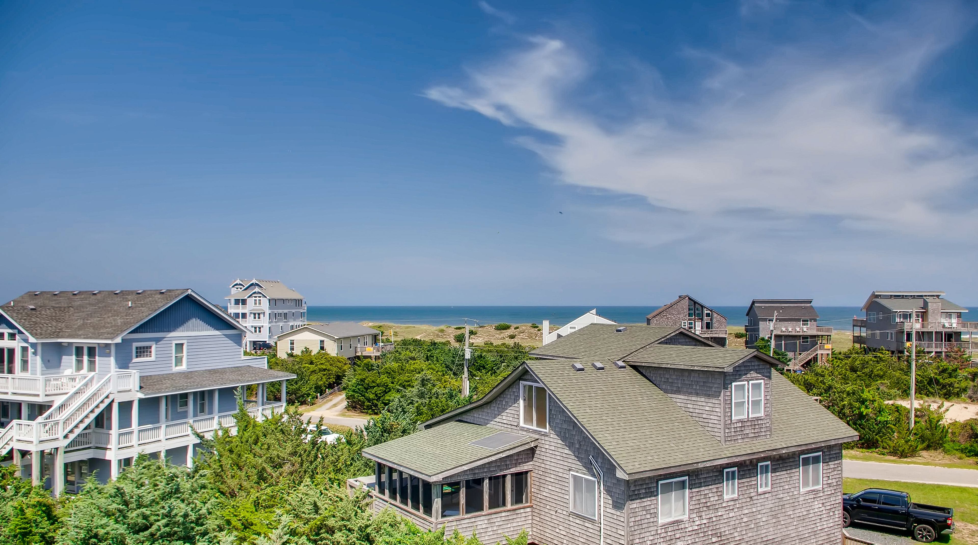 A coastal residential area with houses and a beach in the background.