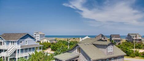 A coastal residential area with houses and a beach in the background.