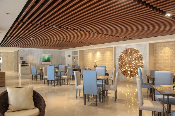 A modern hotel lobby with a wooden ceiling, a large decorative light fixture, and a seating area with chairs and tables. - Acacia Hotel Bacolod (Bacolod)