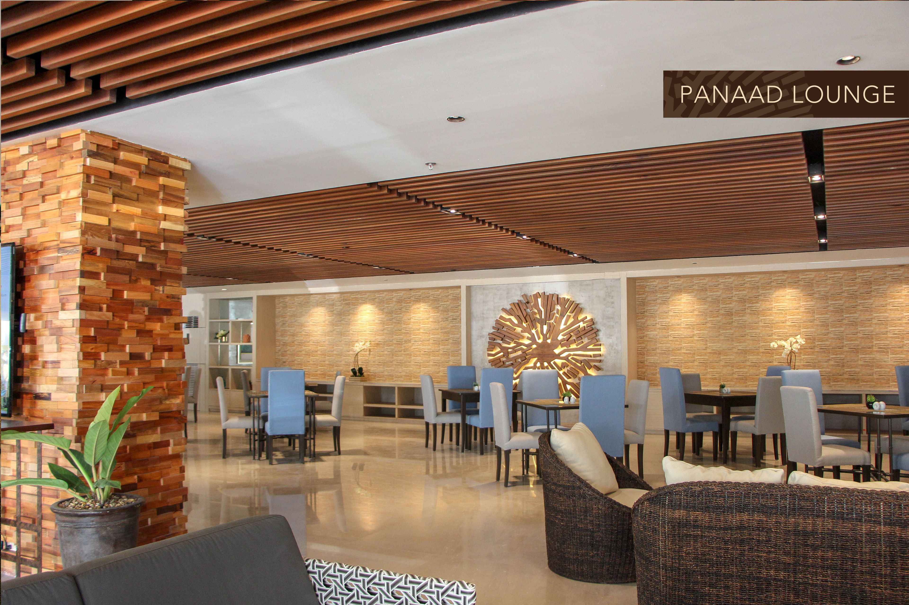 A modern lounge with wooden paneling, a large decorative wall piece, and comfortable seating areas.