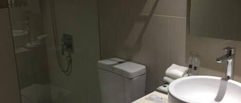 A modern bathroom with a glass-enclosed shower, a toilet, a sink, and a towel rack.