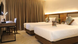 Habitación de hotel con dos camas, un escritorio y una televisión.