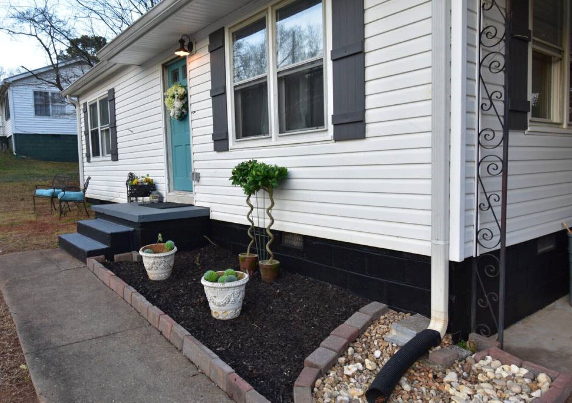 A house with a front porch, steps leading to the door, and potted plants.