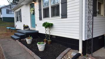 A house with a front porch, steps leading to the door, and potted plants.