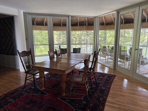 A dining area with a wooden table and chairs, a patterned rug, and large sliding glass doors leading to an outdoor deck.