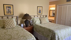 Une chambre d’hôtel avec deux lits, une table de chevet avec une lampe, un miroir et une armoire.
