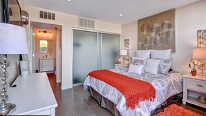 A modern bedroom with a large bed, a desk, and a wardrobe.