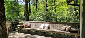 Relax on the bench surrounded by lush greenery and trees.