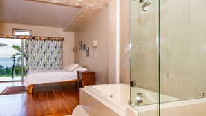 A bedroom with a large bed, a glass shower enclosure, and a view of the outdoors. - LARGE BEAUTIFUL CONDO SUITE 2B/2B IN LAKE ARENAL (Tilaran)