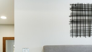 Un dormitorio con una cama, una mesita de noche con lámpara, una planta en maceta y una obra de arte en la pared.