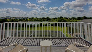 Un balcon donnant sur un terrain de sport, avec des balustrades blanches et une petite table.