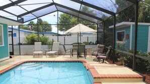 A swimming pool with a glass enclosure, surrounded by outdoor furniture and a patio area.