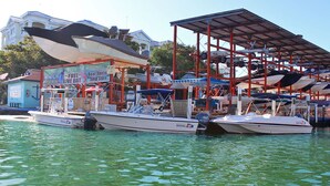 A marina with several boats docked, a boat rental sign, and a building with a signboard.